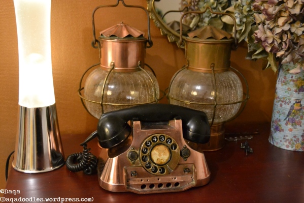 One polished and one unpolished ship lantern and a copper telephone.